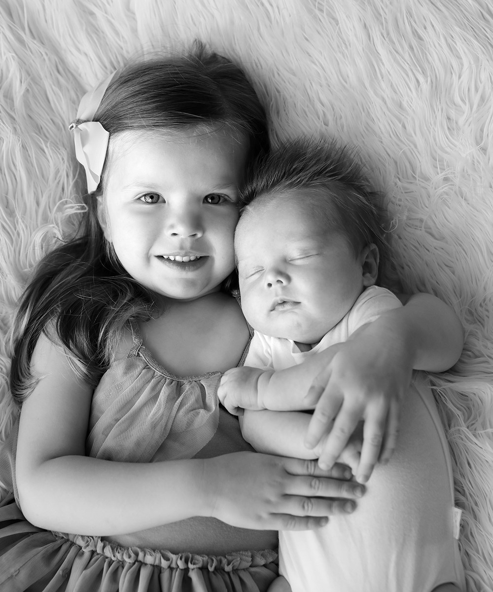 Newborn baby with older sibling in BW